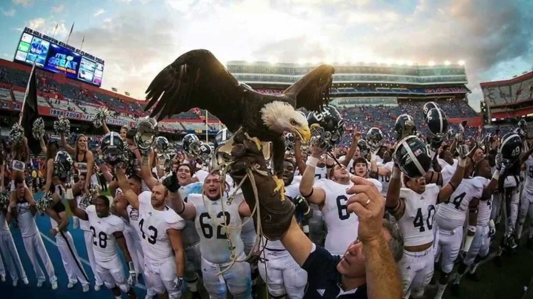 Georgia Southern's mascot, Freedom, with football players, stadium, cheerleaders, and fans in the background. 